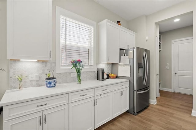 kitchen with white cabinets, backsplash, light hardwood / wood-style floors, and stainless steel fridge with ice dispenser