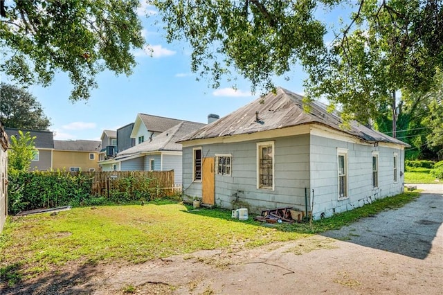 rear view of property featuring a lawn, driveway, and fence