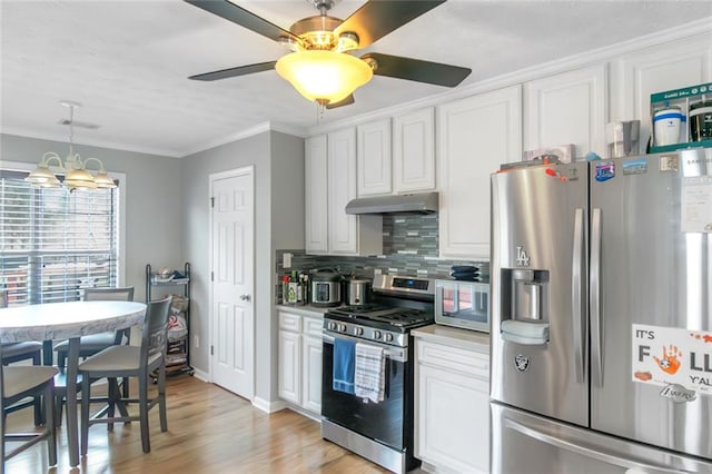147 Midland Dr, Stockbridge, GA 30281 - kitchen featuring stainless steel appliances, under cabinet range hood, ornamental molding, a chandelier, and white cabinetry