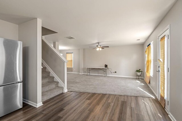 unfurnished living room with visible vents, a ceiling fan, wood finished floors, stairway, and baseboards