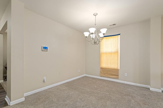 spare room with a notable chandelier, visible vents, baseboards, and carpet