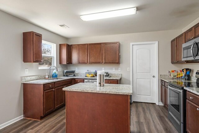 kitchen featuring visible vents, a kitchen island, dark wood-type flooring, stainless steel appliances, and a sink