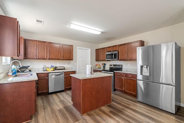 kitchen with visible vents, a sink, a center island, stainless steel appliances, and dark wood-style flooring