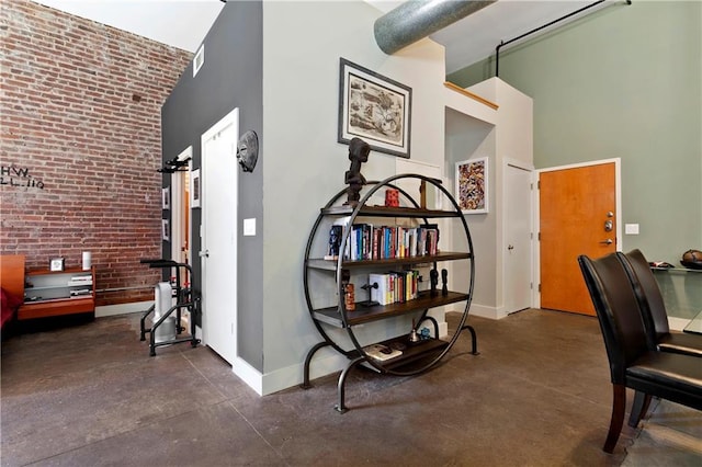 office space with brick wall, visible vents, baseboards, a towering ceiling, and finished concrete floors