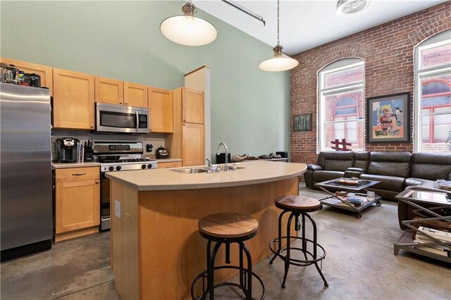 kitchen with an island with sink, a kitchen breakfast bar, brick wall, dishwasher, and sink