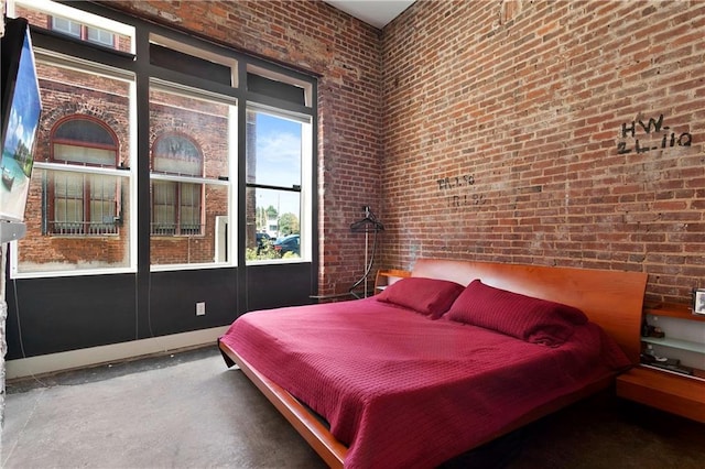 bedroom featuring concrete floors, brick wall, and a high ceiling