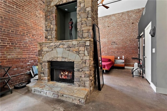 unfurnished living room featuring concrete flooring, ceiling fan, a stone fireplace, and baseboards