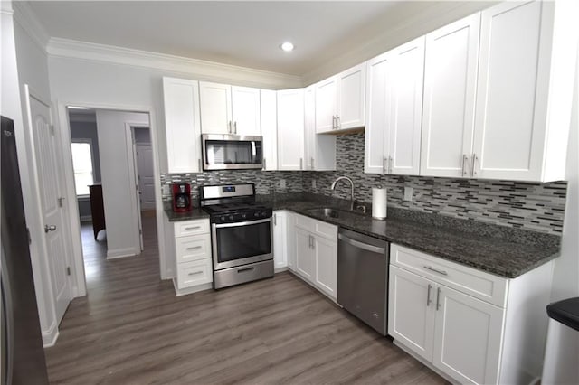 kitchen with dark wood-type flooring, dark stone counters, sink, appliances with stainless steel finishes, and white cabinetry