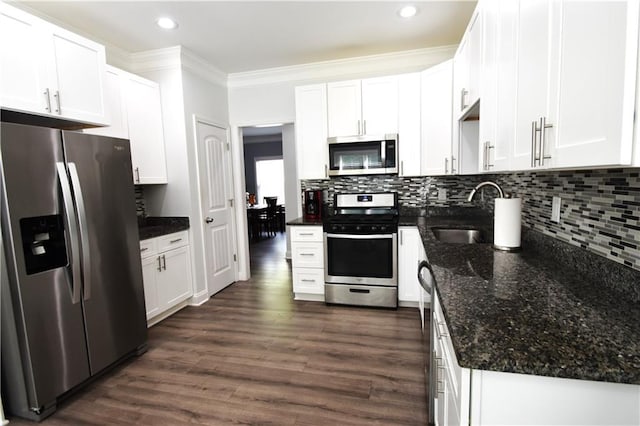 kitchen featuring white cabinets, appliances with stainless steel finishes, decorative backsplash, and dark stone counters