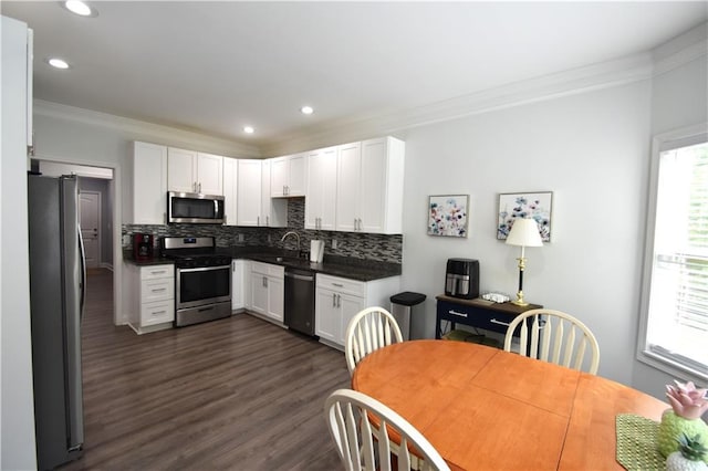 kitchen featuring decorative backsplash, white cabinetry, ornamental molding, and appliances with stainless steel finishes