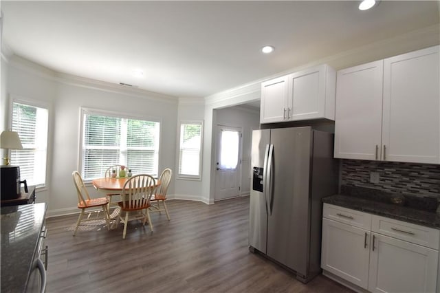 kitchen with decorative backsplash, stainless steel fridge, white cabinetry, and dark stone counters