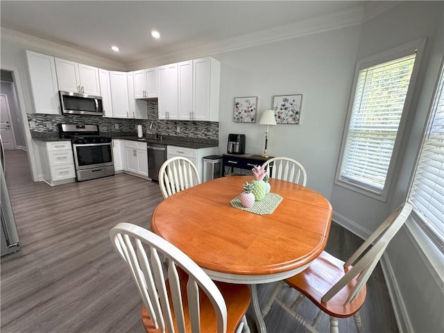 dining space featuring dark hardwood / wood-style floors, ornamental molding, and sink