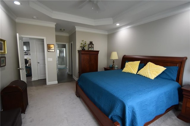 carpeted bedroom featuring ceiling fan, a raised ceiling, ornamental molding, and connected bathroom