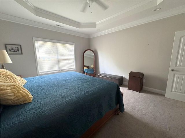 carpeted bedroom with a tray ceiling, ceiling fan, and crown molding