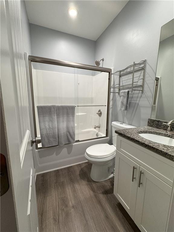 full bathroom with shower / bath combination with glass door, vanity, hardwood / wood-style flooring, and toilet