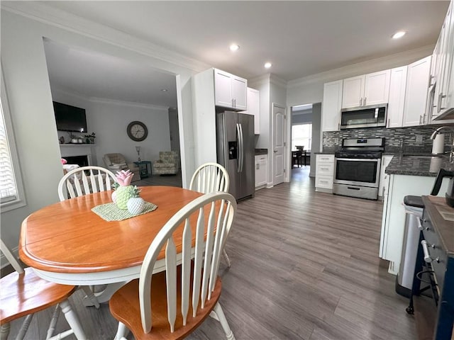 dining space with hardwood / wood-style flooring, ornamental molding, and sink