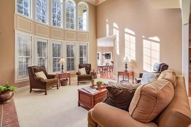 carpeted living room with a high ceiling, a healthy amount of sunlight, and a notable chandelier