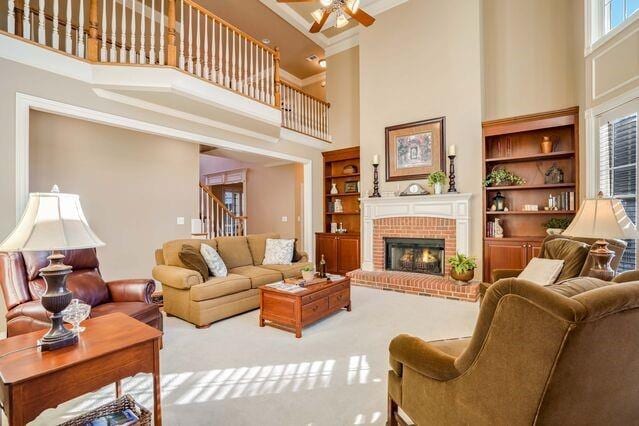 living room with a high ceiling, built in shelves, ornamental molding, a fireplace, and a wealth of natural light