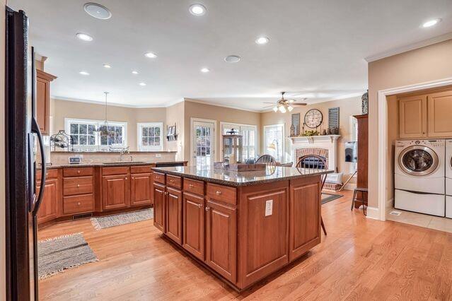 kitchen with black refrigerator, sink, washer and dryer, decorative light fixtures, and a kitchen island