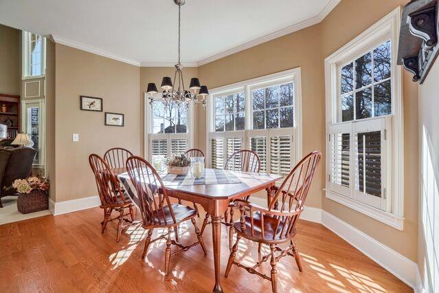 dining area with a notable chandelier, light wood-type flooring, and crown molding