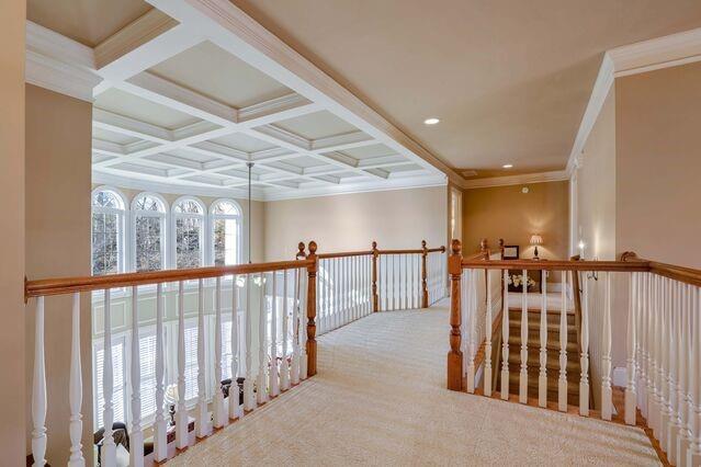 hallway featuring beam ceiling, crown molding, light carpet, and coffered ceiling