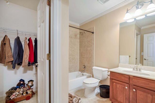 full bathroom with tile patterned floors, ornamental molding, vanity, toilet, and tiled shower / bath