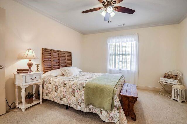 carpeted bedroom with ceiling fan and crown molding