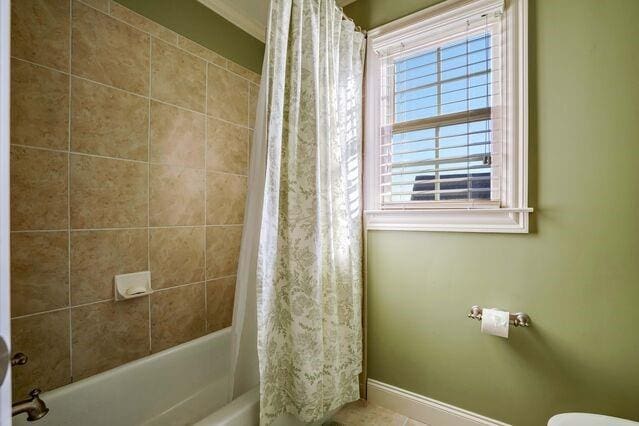 bathroom with toilet, shower / bathtub combination with curtain, and crown molding