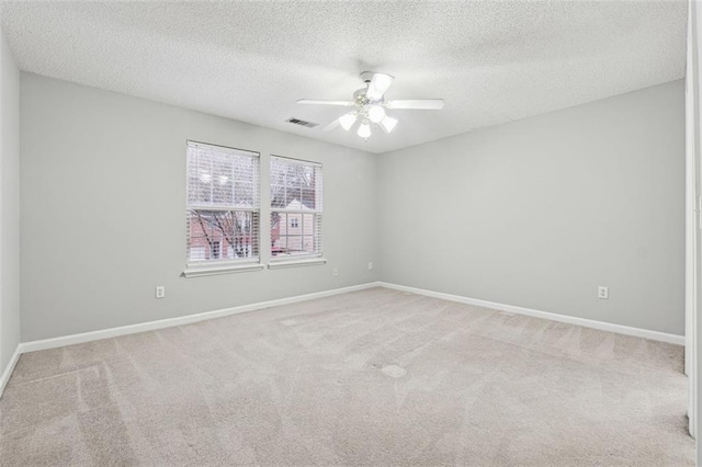 empty room featuring a textured ceiling, ceiling fan, and light carpet