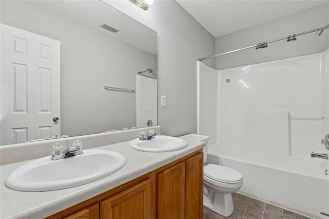 full bathroom with tub / shower combination, tile patterned floors, a textured ceiling, toilet, and vanity