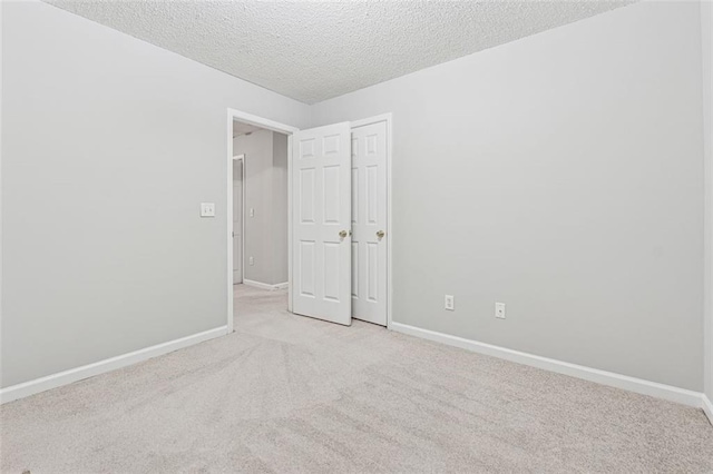 spare room featuring light carpet and a textured ceiling