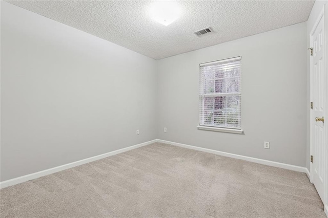 spare room featuring a textured ceiling and light carpet