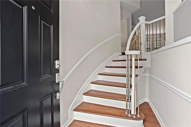 entrance foyer with baseboards, wood finished floors, and stairs