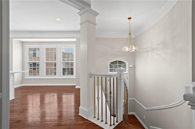 entrance foyer with baseboards, ornamental molding, wood finished floors, a notable chandelier, and ornate columns