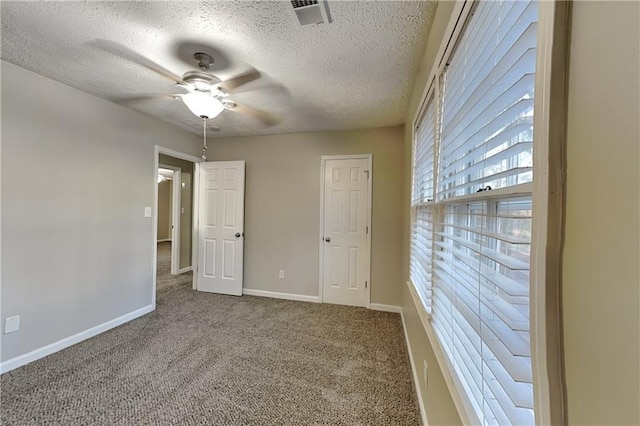 unfurnished bedroom featuring a textured ceiling, carpet flooring, visible vents, and baseboards