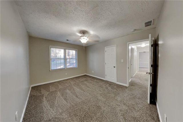 carpeted spare room with visible vents, a textured ceiling, and baseboards