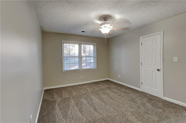 empty room featuring carpet, visible vents, a textured ceiling, and baseboards