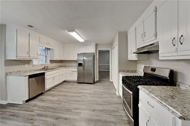 kitchen featuring appliances with stainless steel finishes, white cabinetry, a sink, and under cabinet range hood