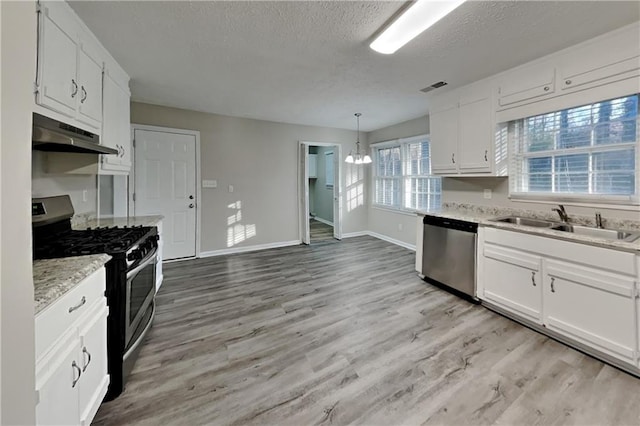 kitchen with pendant lighting, under cabinet range hood, appliances with stainless steel finishes, and white cabinets