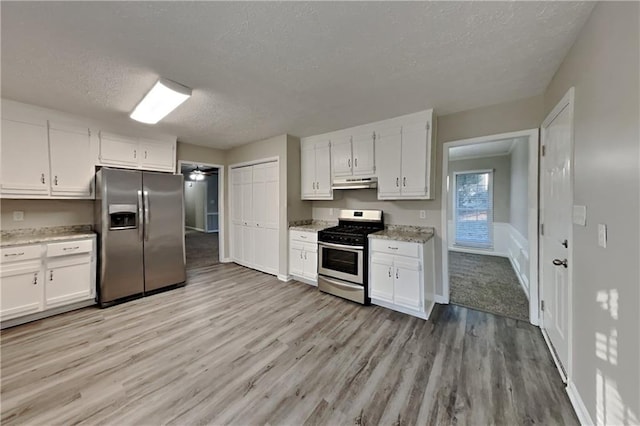 kitchen featuring under cabinet range hood, appliances with stainless steel finishes, light wood-style flooring, and white cabinets