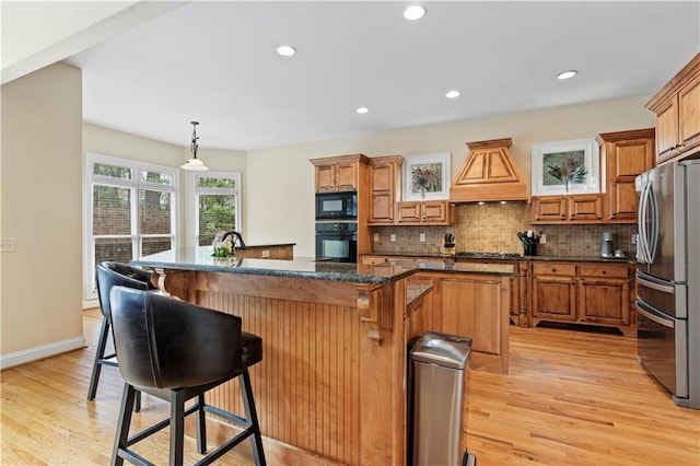 5955 Manchester Ln, Gainesville, GA 30506 - kitchen featuring black appliances, a center island, premium range hood, light wood-style flooring, and recessed lighting