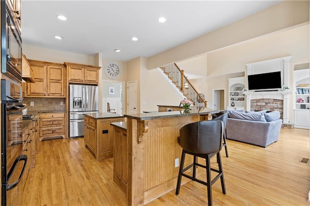5955 Manchester Ln, Gainesville, GA 30506 - kitchen with stainless steel refrigerator with ice dispenser, a center island, a kitchen bar, light wood-style floors, and tasteful backsplash