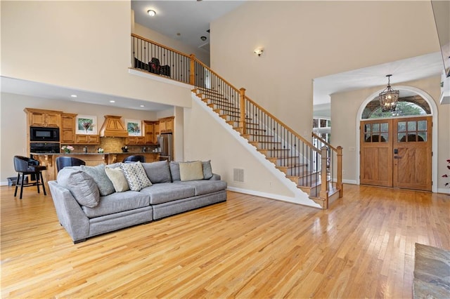 5955 Manchester Ln, Gainesville, GA 30506 - living room with light wood-style floors, a chandelier, stairs, a high ceiling, and baseboards