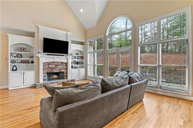 5955 Manchester Ln, Gainesville, GA 30506 - living room featuring high vaulted ceiling, light wood finished floors, a stone fireplace, and built in shelves