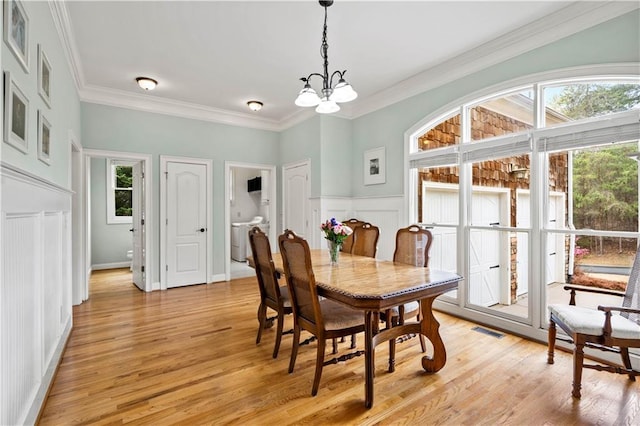 5955 Manchester Ln, Gainesville, GA 30506 - dining room featuring a chandelier, light wood finished floors, crown molding, washer / dryer, and a decorative wall
