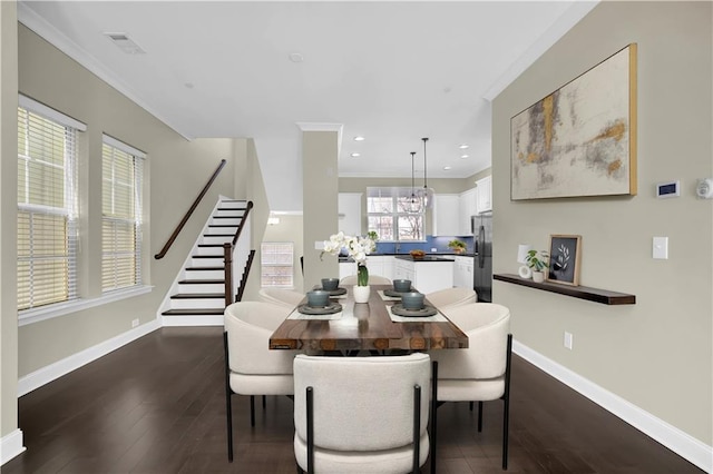 dining space featuring visible vents, dark wood finished floors, crown molding, baseboards, and stairs