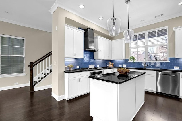 kitchen with crown molding, wall chimney range hood, visible vents, and appliances with stainless steel finishes