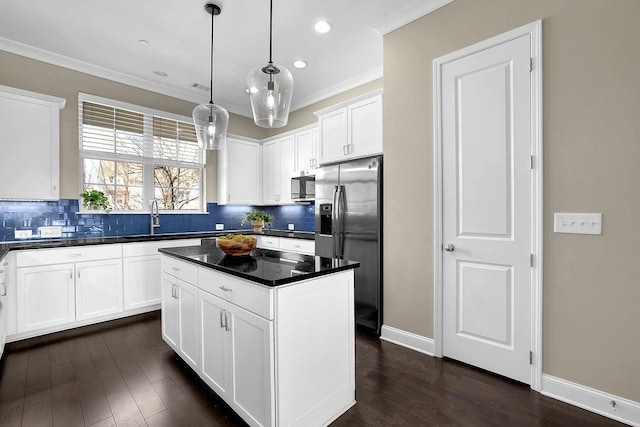 kitchen with dark countertops, ornamental molding, stainless steel appliances, and a sink