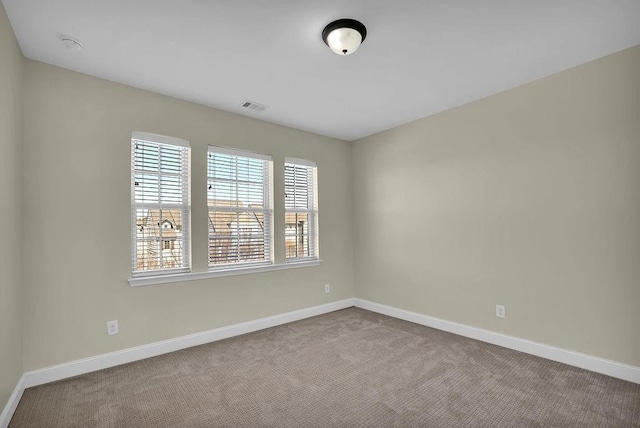 carpeted spare room with visible vents and baseboards