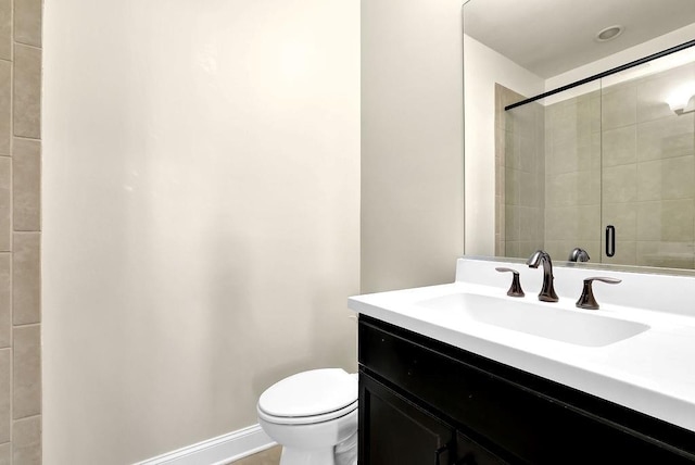 full bathroom with vanity, toilet, baseboards, and a tile shower